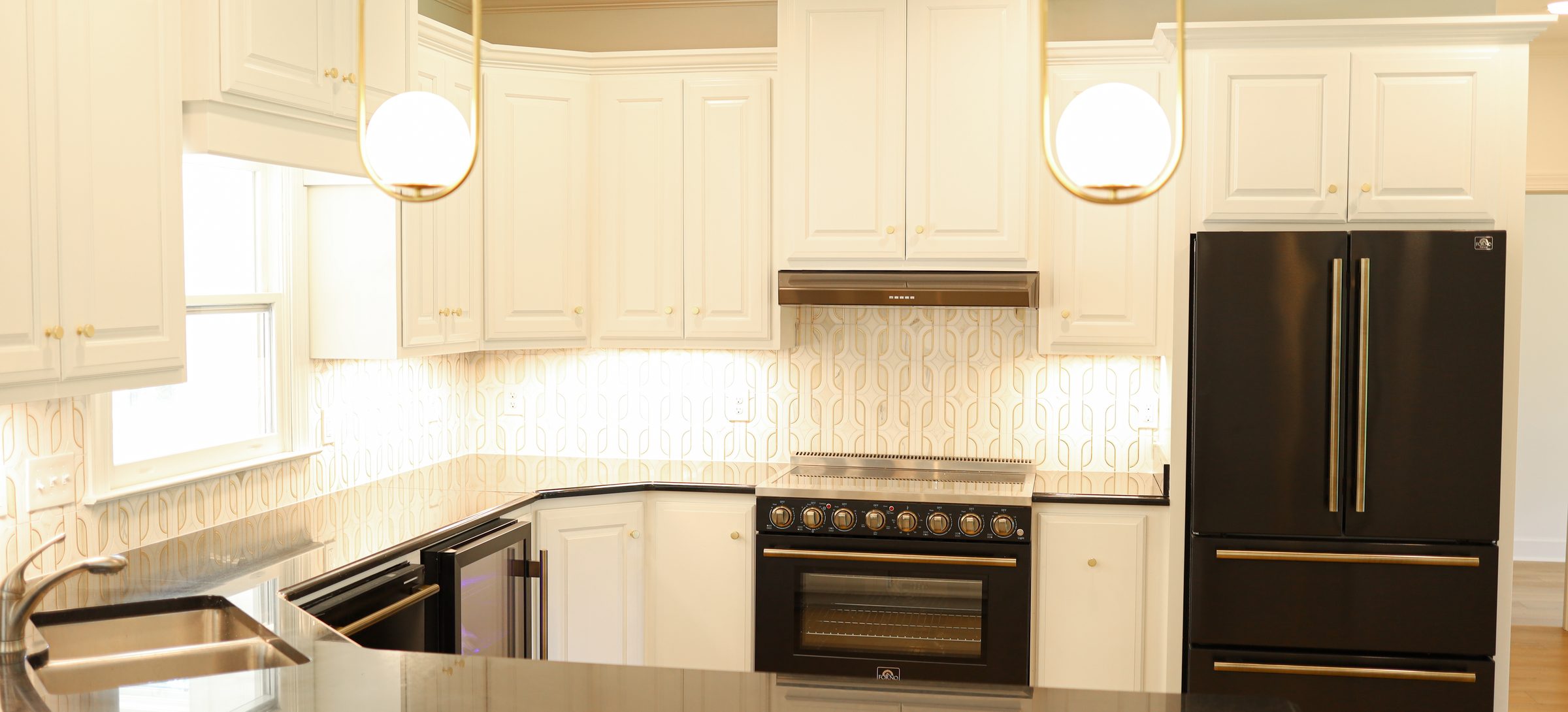 Custom white kitchen cabinetry with brass pendant lighting and black panel-front appliances